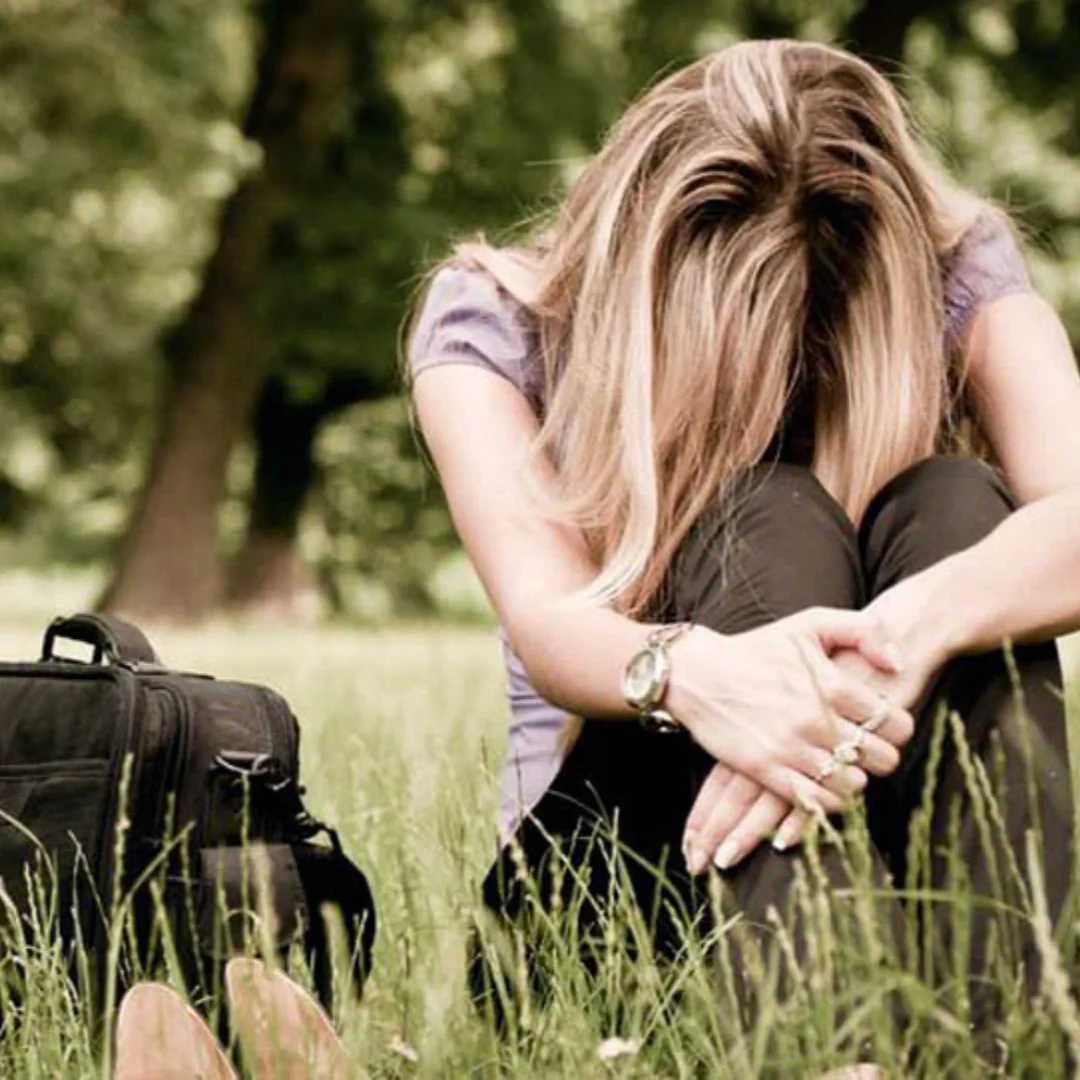 woman sitting on the grass with her head down