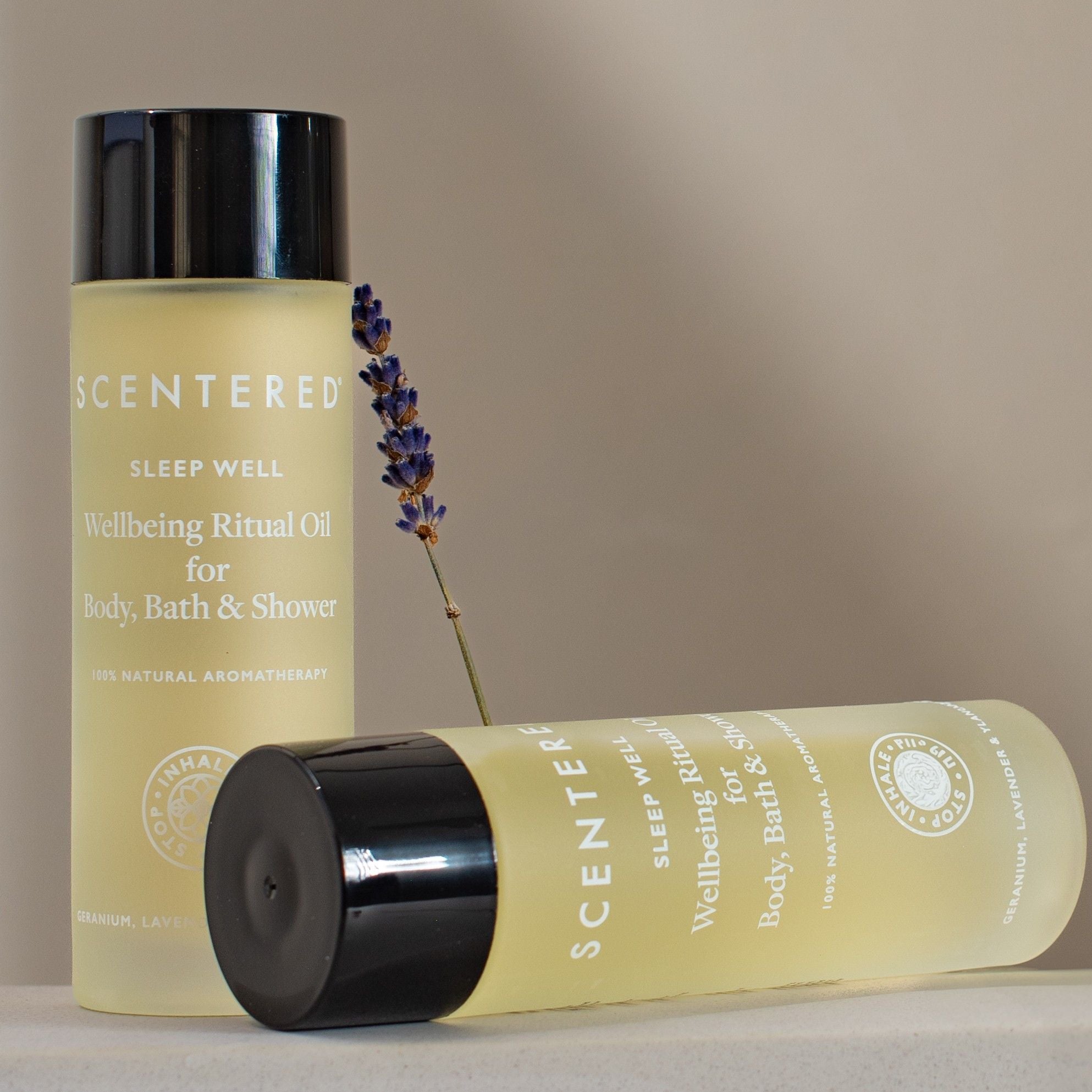 Two Scentered Sleep Well Body oil in bottles one on it's side with lavender on a beige background