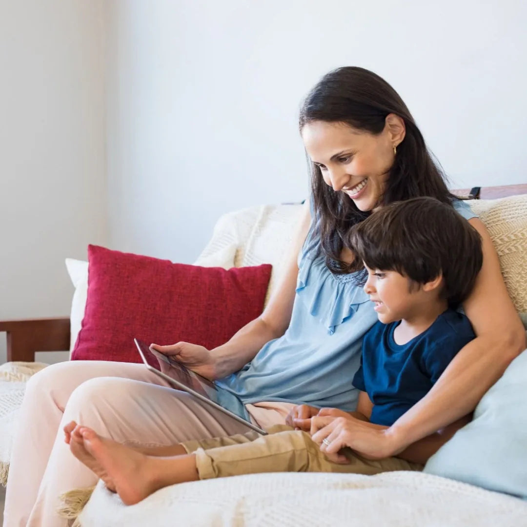 Mom and son sitting on a couch reading and smiling