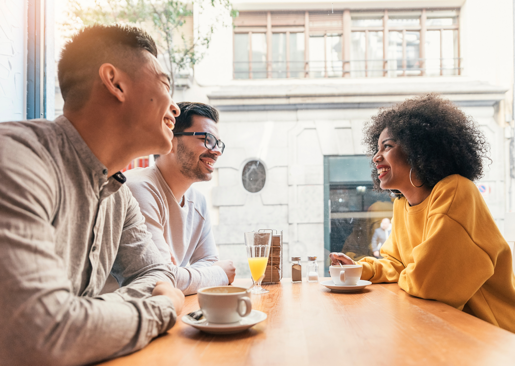 Three friends enjoying coffee and smiling 