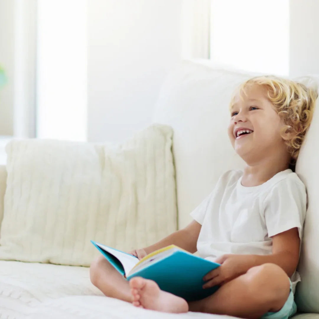 Toddler sitting and smiling holding a book