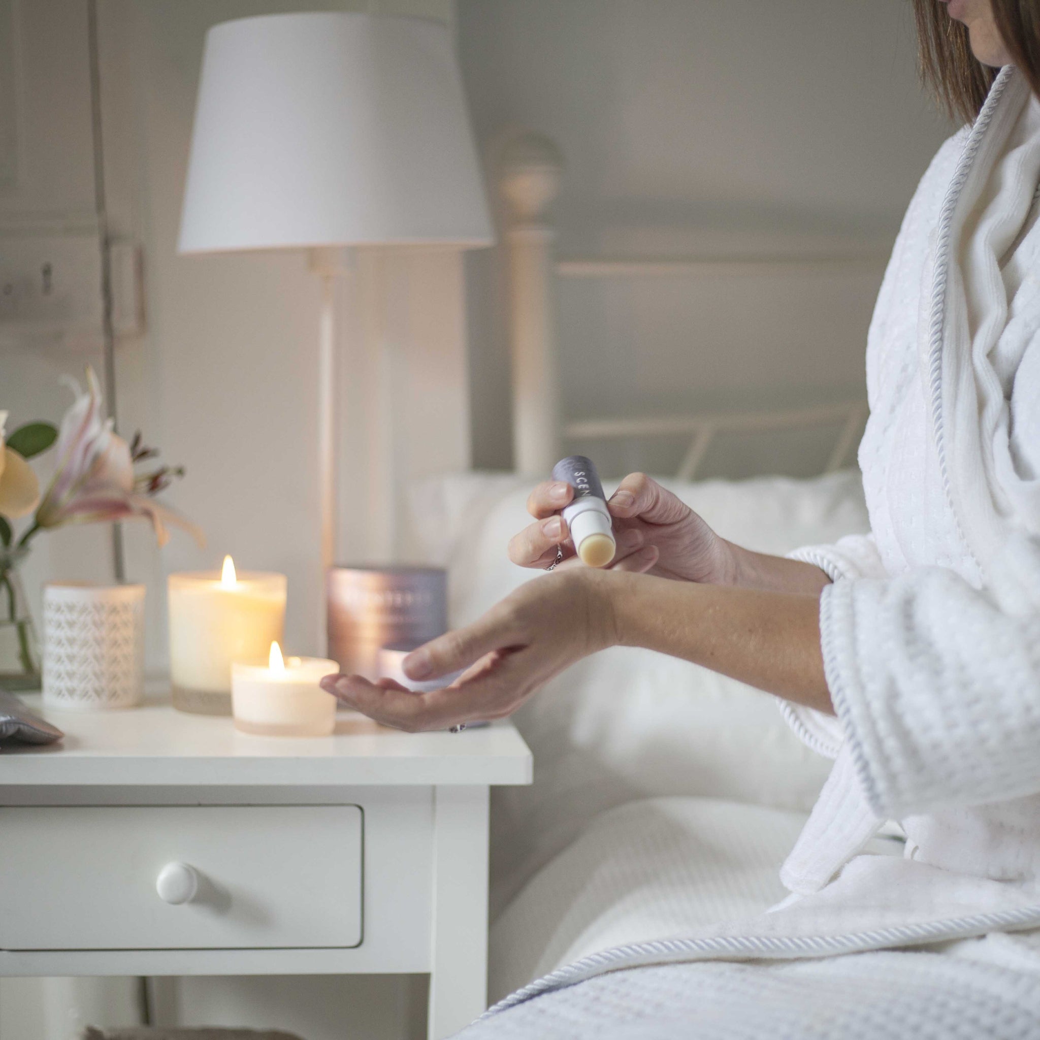 woman applying aromatherapy balm in bed