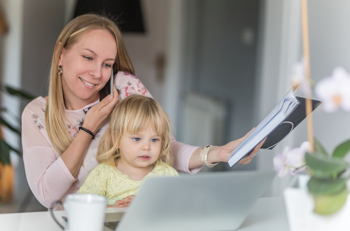 mom holding toddler while working