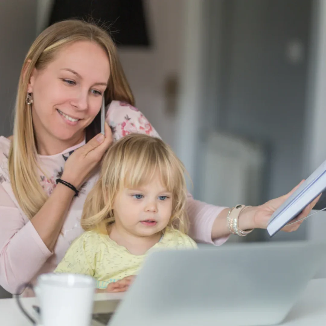 mom holding toddler while working