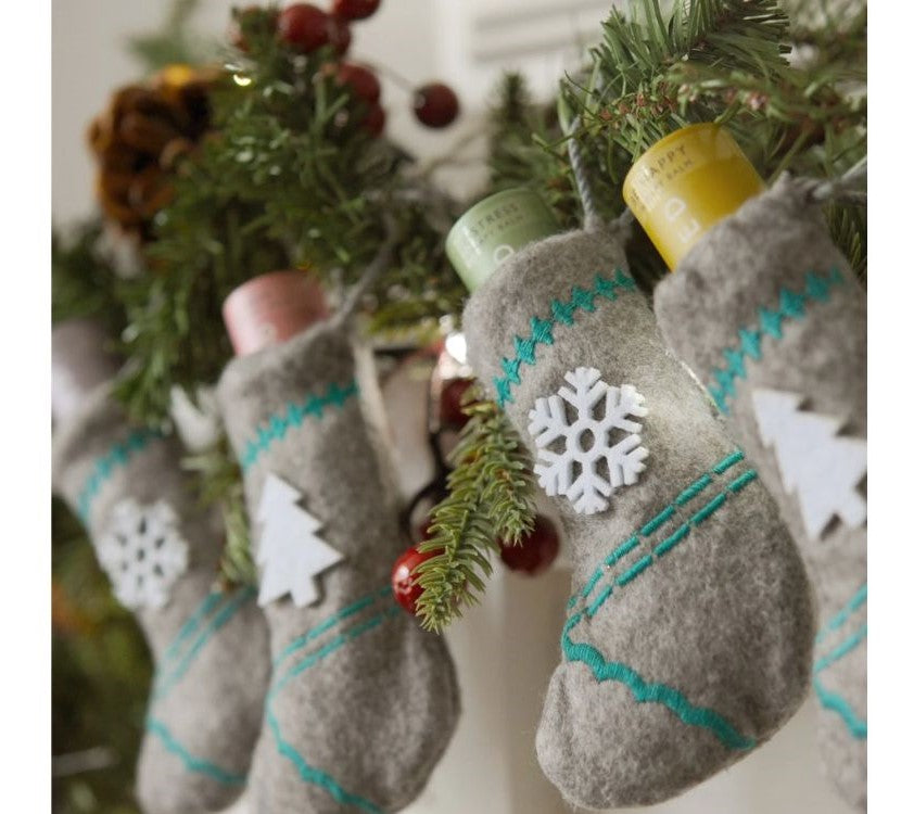 Scentered Aromatherapy Balm stocking set, 4 stockings with balm, each one hanging from a mantle piece garland 
