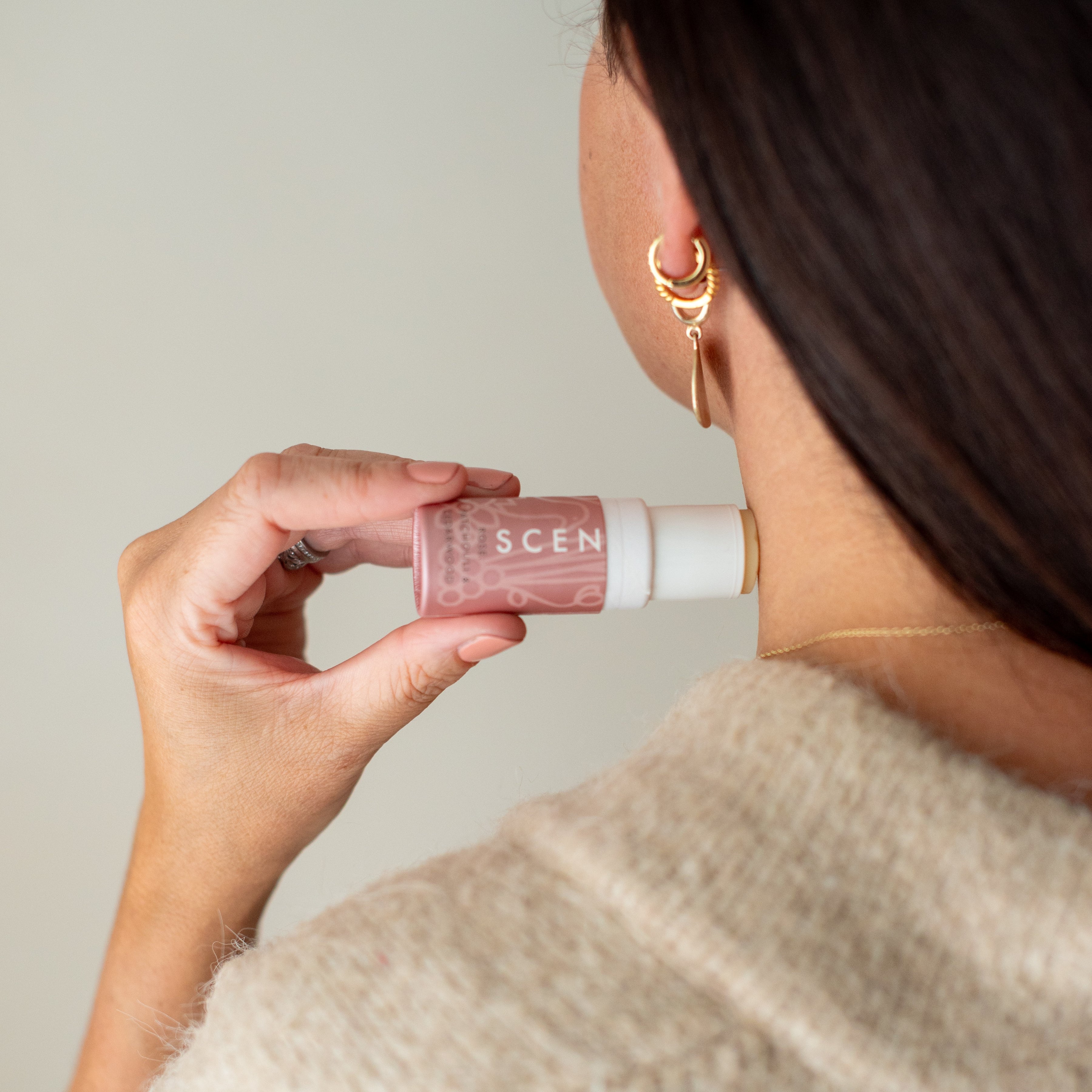A woman holding a love balm to use on her neck