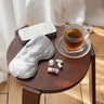Goodnight Gift Set with Silk eye mask, Sleep Well Mini balm and ear plugs laid out on table next to a cup of herbal tea