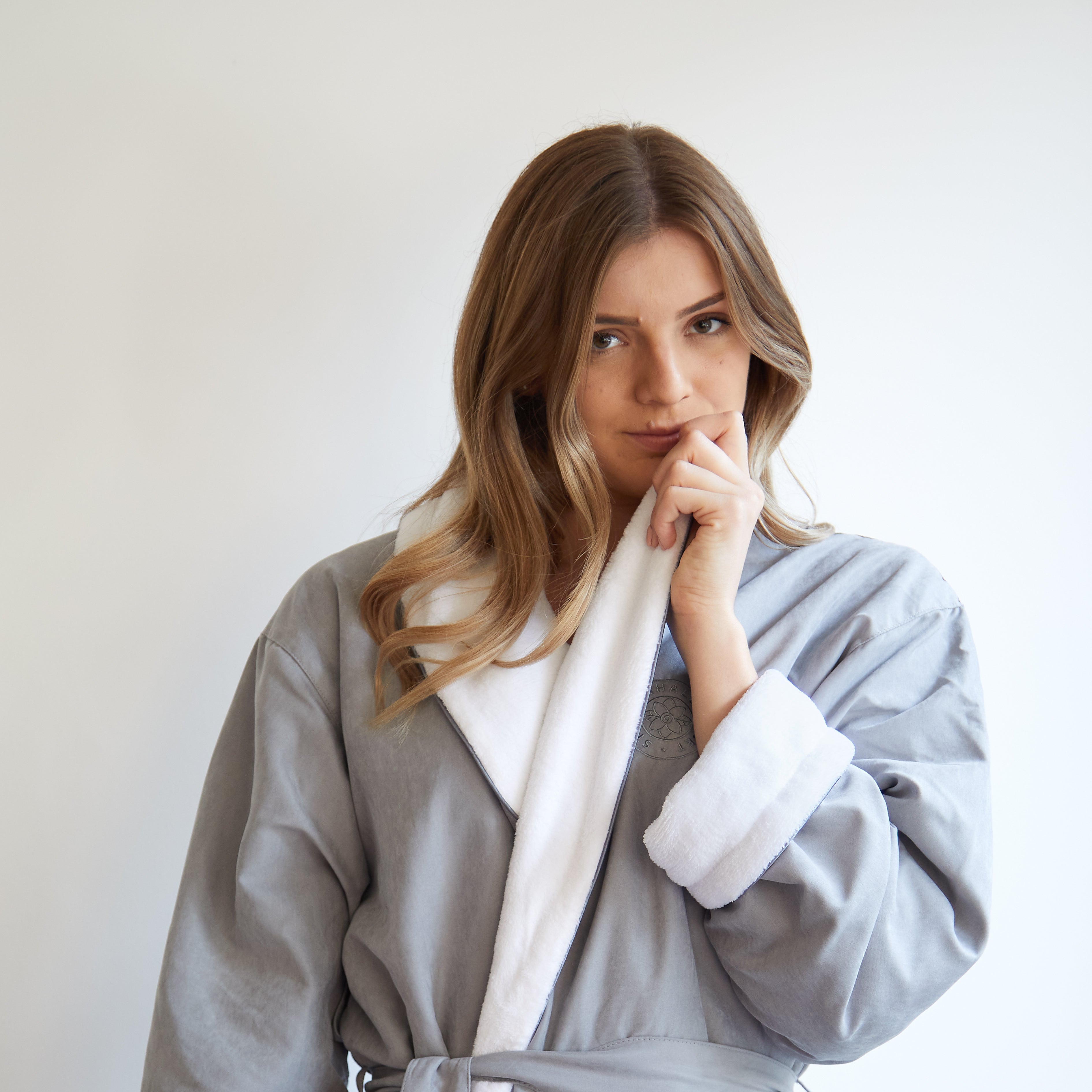 Woman wearing a gray bathrobe on a plain background