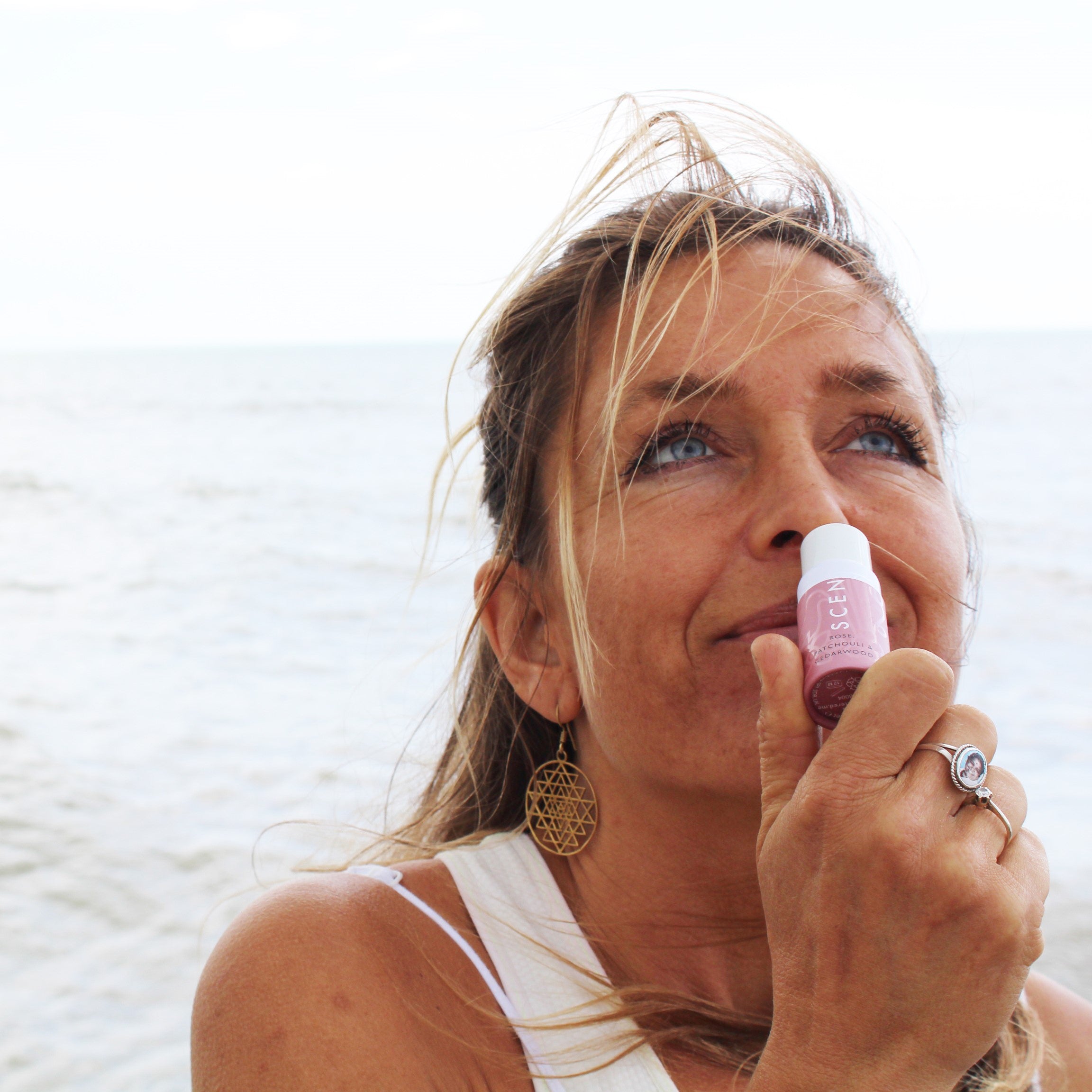Lady taking a moment to Stop. Inhale. Reset. With a Scentered Love Balm by the sea