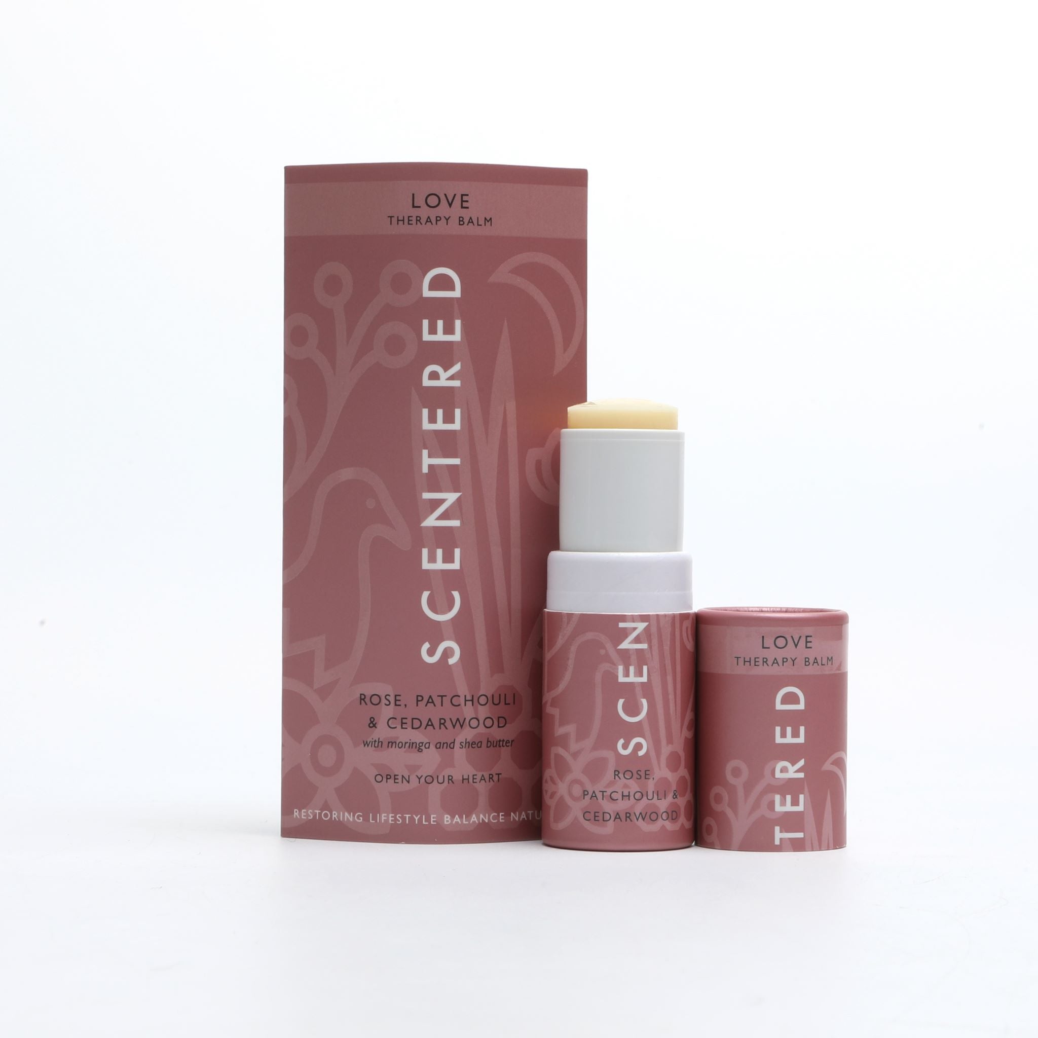 Love Aromatherapy Balm with cap off and twisted up with eco sleeve packaging on a white background