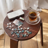 Small wooden table with a puzzle, a tea cup and a change of pace balm set on a light wood floor.