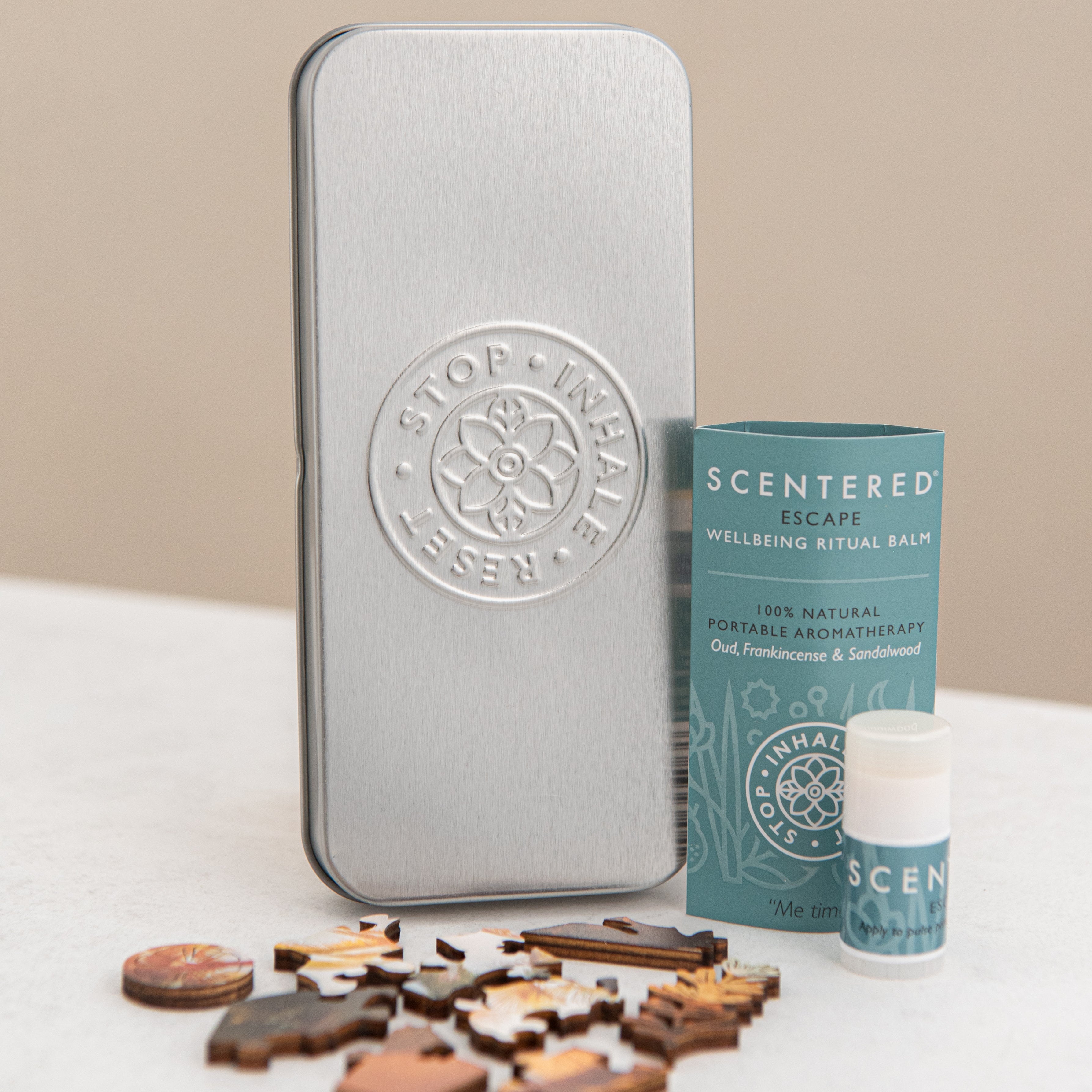 There’s a Scentered tin set, an Escape mini balm standing upright, and a puzzle—all laid out together.