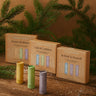 Three boxes of 'Scentered' products with happy balm, de-stress balm and sleep well balm on a wooden surface with greenery in the background.